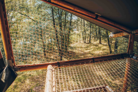 Udsigt gennem et net fra en safaritelts terrasse ved Wilsumer Berge i Tyskland, omgivet af skov.