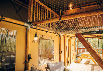 Interieur van een safaritent met houten frame, netloft en buitenterras op Wilsumer Berge, Duitsland.