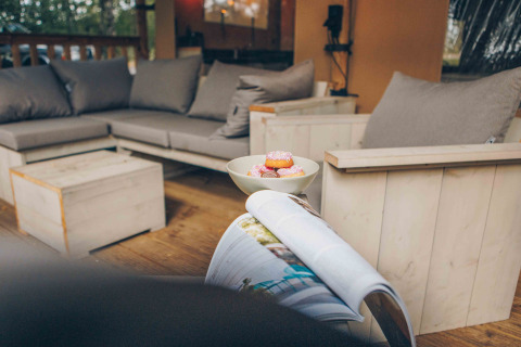 Komfortabelt opholdsområde i en safaritelte ved Wilsumer Berge, Tyskland, med sofa, lænestol og snacks.