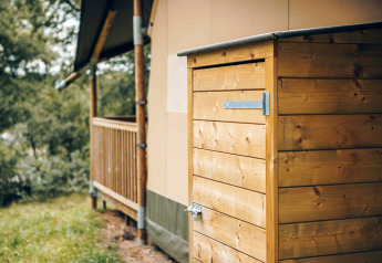 Houten schuurtje bij een safaritent in Wilsumer Berge, Duitsland, omringd door groene natuur.