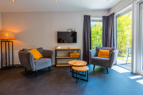 Salon moderne à Wellness Lodge, Vakantiepark De Wiltzangh, Pays-Bas, avec grandes fenêtres et fauteuils confortables.