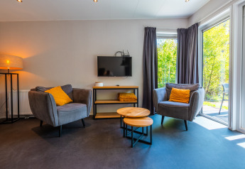 Salón moderno en Wellness Lodge, Vakantiepark De Wiltzangh, Países Bajos, con grandes ventanas y cómodos sillones.