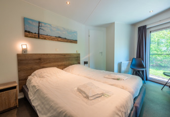 Moderne lodge på Vakantiepark De Wiltzangh, Nederlandene, med komfortable enkeltsenge og store vinduer.