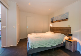 Chambre moderne dans la Wellness Lodge au Vakantiepark De Wiltzangh, Pays-Bas, avec un lit double confortable.