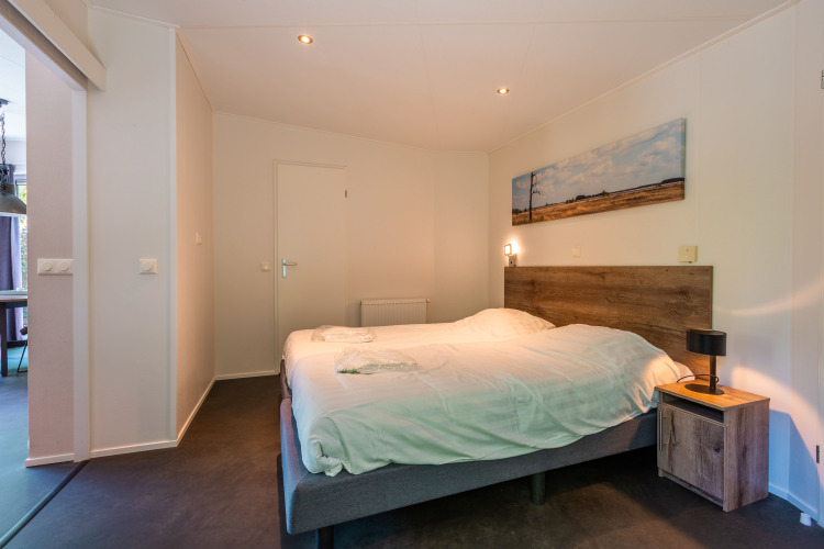 Modernes Schlafzimmer in der Wellness Lodge im Vakantiepark De Wiltzangh, Niederlande, mit Doppelbett.