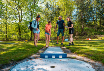 Familia disfruta de minigolf al aire libre en Wellness Lodge del Vakantiepark De Wiltzangh, Países Bajos.