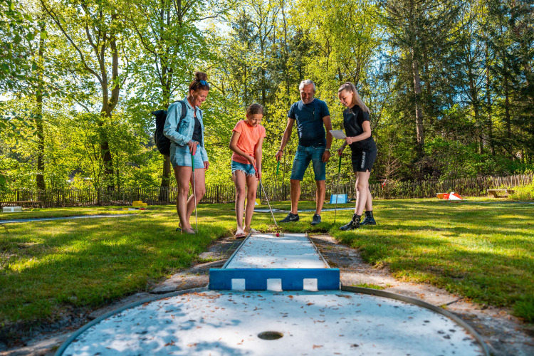 Familie spielt Minigolf an einem sonnigen Tag bei der Wellness Lodge im Vakantiepark De Wiltzangh, Niederlande.