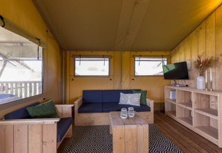 Interior de una tienda safari en Safarilodge Gazelle, Vakantiepark IJsselhof, Países Bajos, con muebles de madera.