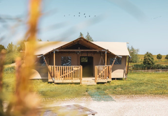 Tenda safari Safarilodge Impala al Vakantiepark IJsselhof nei Paesi Bassi, circondata dal verde.