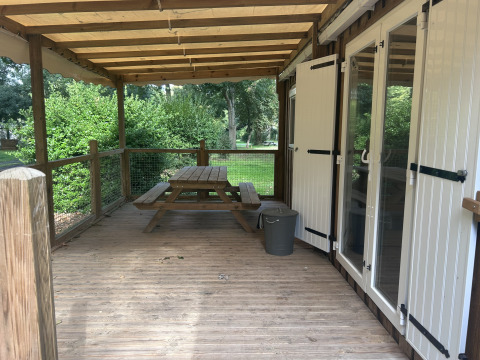 Træterrasse med bænk, overdækning og udsigt til grøn natur ved Cottage på Camping Seasonova du Chêne.