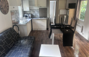 Interior of Cottage at Camping Seasonova du Chêne in France, showing kitchen, sofa, and dining area.