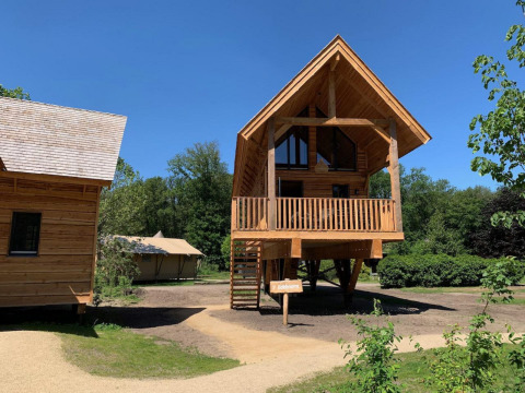 Tree house named Heydehuis + Jacuzzi at Sandberghe in the Netherlands on a sunny day with blue sky.