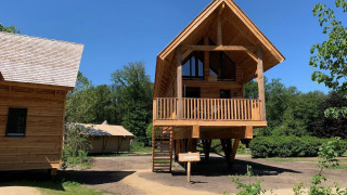 Boomhut Heydehuis + Jacuzzi bij Sandberghe in Nederland op een zonnige dag met een strakblauwe lucht.