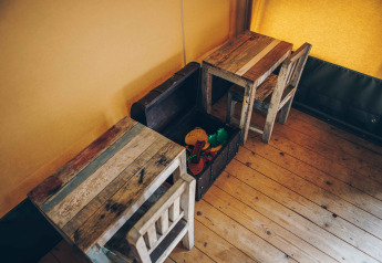 Børnebord og stole i træ med legetøjskiste i et safari-telt på Wilsumer Berge i Tyskland.