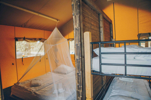 Innenaufnahme vom Safari-Zelt bei Wilsumer Berge in Deutschland, mit Bett, Moskitonetz und Etagenbetten.