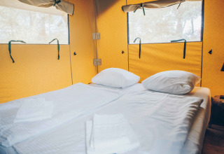 Innenansicht eines Safari-Zeltes mit Doppelbett im Wilsumer Berge, Deutschland, bei Tageslicht.