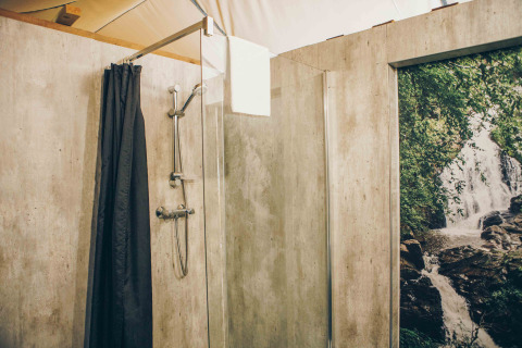 Badezimmer im Safarizelt bei Wilsumer Berge, Deutschland, mit moderner Dusche und Naturfototapete.
