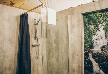 Badezimmer im Safarizelt bei Wilsumer Berge, Deutschland, mit moderner Dusche und Naturfototapete.