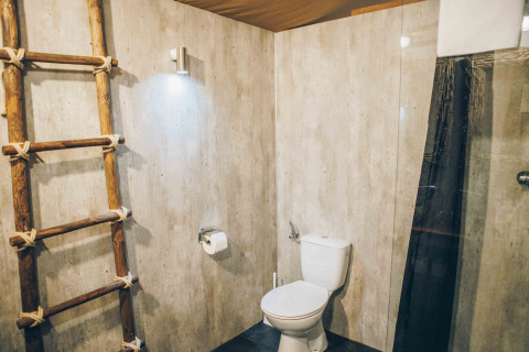 Modernes Badezimmer mit Holzleiter, WC und schlichtem Licht in einem Safari-Zelt bei Wilsumer Berge.