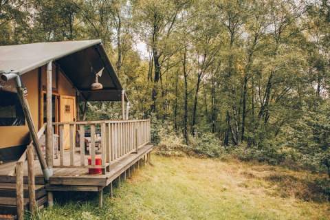 Safari-Zelt am Wilsumer Berge in Deutschland mit Holzveranda und Grünblick auf den Wald im Sommer.