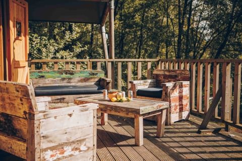 Holzterrasse mit rustikalen Möbeln vor einem Safarizelteingang in Wilsumer Berge, Deutschland.