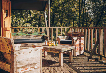 Holzterrasse mit rustikalen Möbeln vor einem Safarizelteingang in Wilsumer Berge, Deutschland.