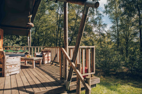 Træterrasse ved en safaritelte på Wilsumer Berge i Tyskland med rustikke møbler i skovomgivelser.