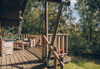 Holzterrasse eines Safarizelts am Wilsumer Berge in Deutschland mit rustikalen Möbeln im Wald.