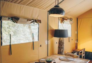 Innenansicht eines Safari-Zelts bei Wilsumer Berge, Deutschland, mit Holztisch und gemütlichem Dekor.