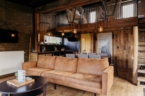 Salon chaleureux du lodge Juttershut à Duynpark Het Zwanenwater, Pays-Bas, avec des touches de bois rustique.