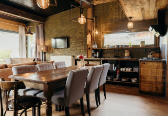 Vista interna di una cucina e zona pranzo accoglienti al lodge Juttershut, Duynpark Het Zwanenwater, Paesi Bassi.