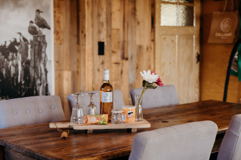Table at Juttershut, Duynpark Het Zwanenwater, Netherlands, with wine, snacks, flowers, and glasses.