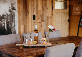 Tavolo al Juttershut, Duynpark Het Zwanenwater, Paesi Bassi, con vino, snack, fiori e bicchieri.