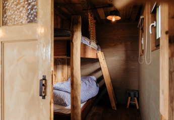 Entrée d'une chambre en bois avec lits superposés et linge à carreaux au Juttershut, Duynpark Het Zwanenwater.