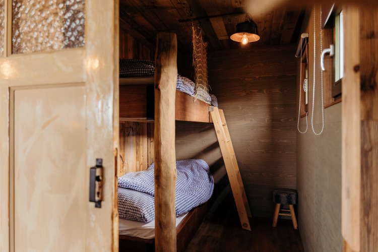 Eingang zu einem gemütlichen Holzraum mit Etagenbetten und karierten Laken im Juttershut, Duynpark Het Zwanenwater.