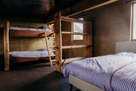 Gezellige slaapkamer in Juttershut, Duynpark Het Zwanenwater, met houten stapelbedden en eenpersoonsbed.
