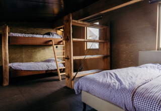 Gezellige slaapkamer in Juttershut, Duynpark Het Zwanenwater, met houten stapelbedden en eenpersoonsbed.