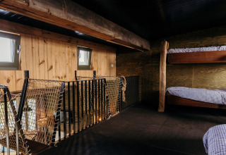 Slaapzolder met houten stapelbedden en touwreling in Juttershut, Duynpark Het Zwanenwater, Nederland.