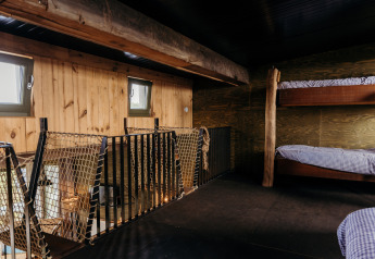 Camera soppalcata con letti a castello in legno e parapetto a rete a Juttershut, Duynpark Het Zwanenwater, NL.
