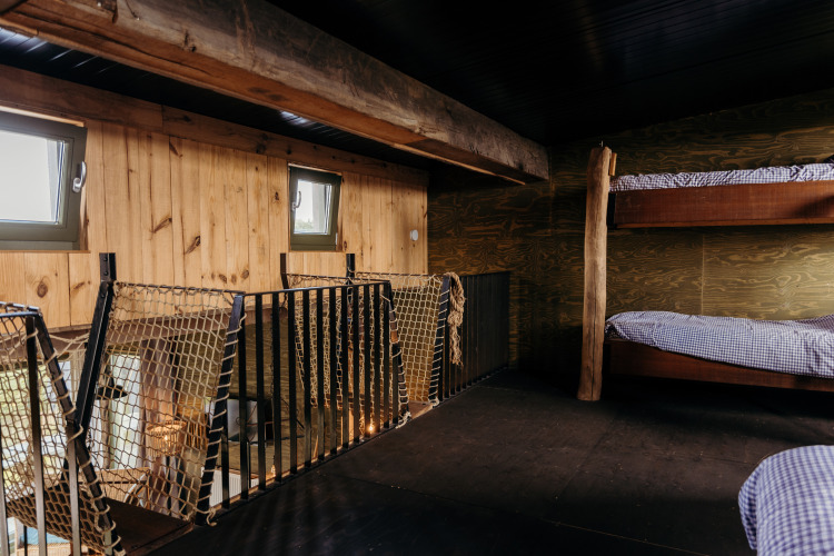 Loftschlafzimmer mit Etagenbetten, Holzwänden und Netzgeländer in Juttershut, Duynpark Het Zwanenwater, NL.