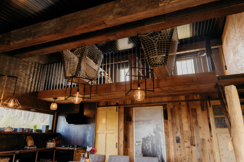 Rustiek interieur van Juttershut-lodge bij Duynpark Het Zwanenwater met netten entresol en houten accenten.