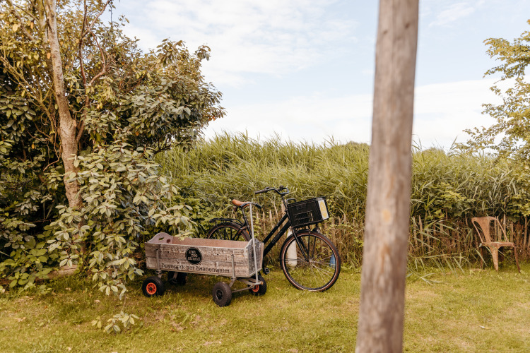Fahrrad mit Holzkiste auf grünem Rasen bei Duynpark Het Zwanenwater, Juttershut Lodge, Niederlande.