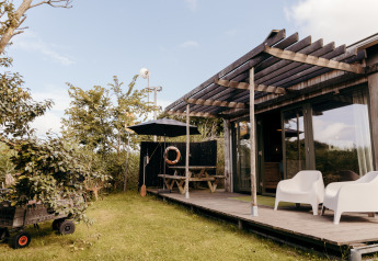 Vista esterna del lodge Juttershut al Duynpark Het Zwanenwater nei Paesi Bassi con terrazza e sedie.