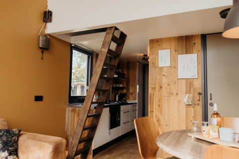 Interno del Rescue cottage a Duynpark Het Zwanenwater, Paesi Bassi, con scala in legno e cucina compatta.