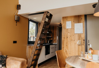 Interno del Rescue cottage a Duynpark Het Zwanenwater, Paesi Bassi, con scala in legno e cucina compatta.