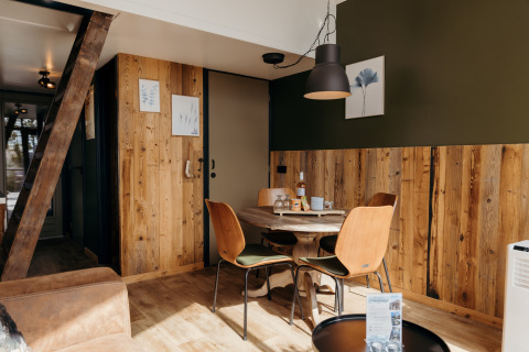Dining area in Rescue Cottage at Duynpark Het Zwanenwater, Netherlands, featuring wood paneling and cozy décor.