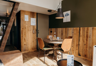 Dining area in Rescue Cottage at Duynpark Het Zwanenwater, Netherlands, featuring wood paneling and cozy décor.