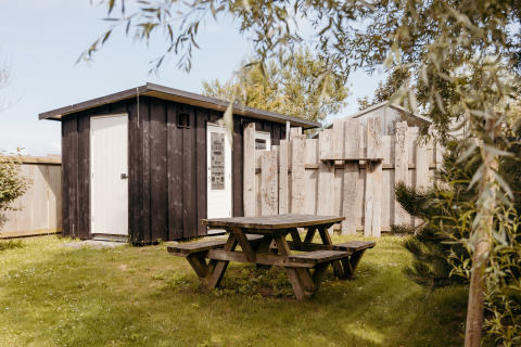 Outdoor picnic table and rustic cabin at the Rescue Cottage in Duynpark Het Zwanenwater, Netherlands.