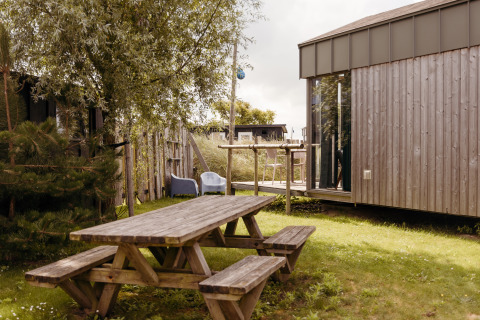 Outdoor area of Rescue cottage, a tiny house at Duynpark Het Zwanenwater, Netherlands, with a picnic table.