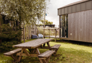 Outdoor area of Rescue cottage, a tiny house at Duynpark Het Zwanenwater, Netherlands, with a picnic table.